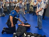 School Resource Officer demonstrating a restraint device called a WRAP. He is demonstrating to the Youth Safety Academy.