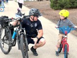 Police Officer on bike patrol talking with a young boy.